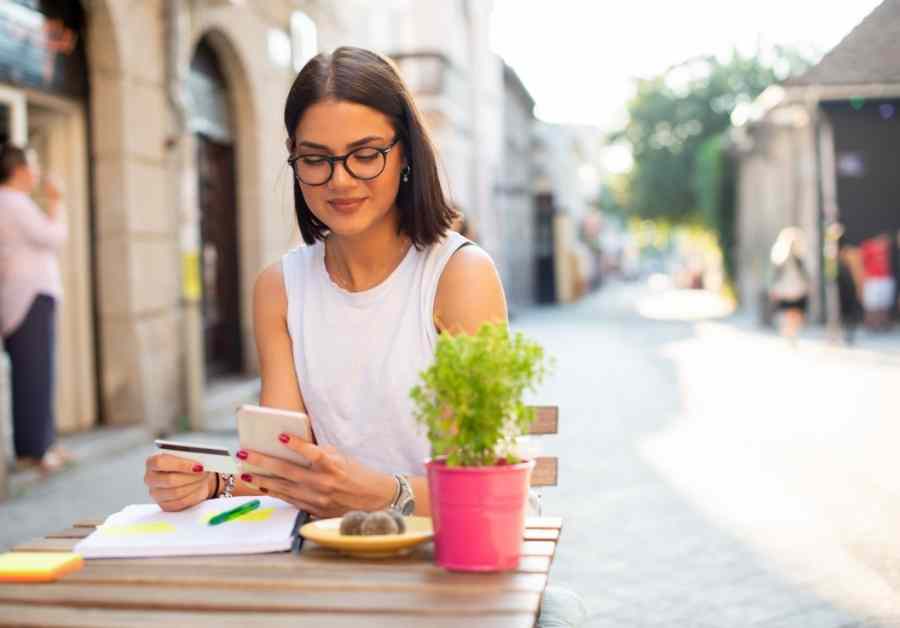 בחורה משלמת לחנות דיגיטלית באינטרנט בבית קפה